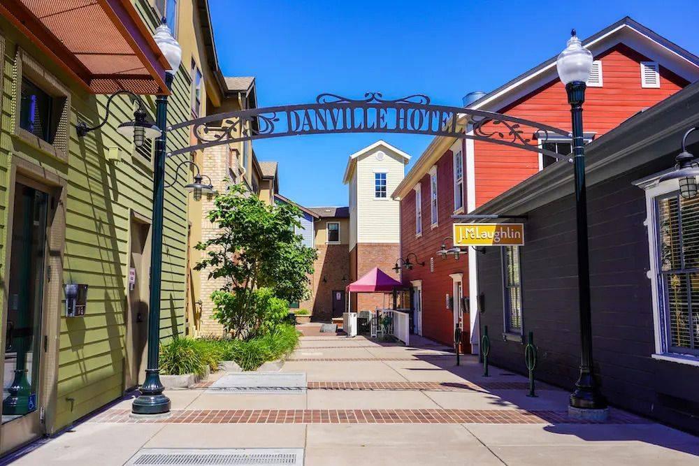 Danville Hotel archway in downtown Danville, California, featuring colorful storefronts, pedestrian walkways, and a charming mixed-use commercial district.