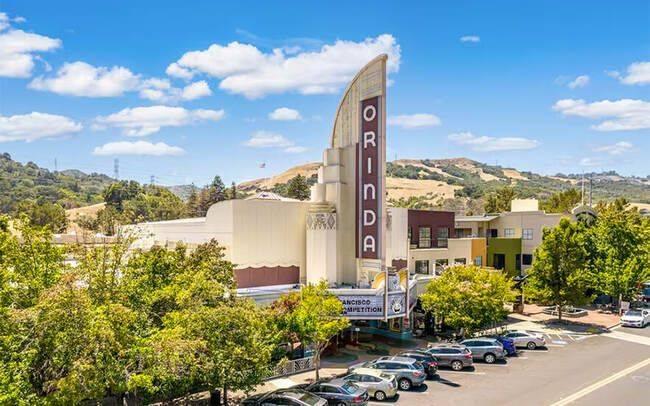 Historic Orinda Theatre in downtown Orinda, California, surrounded by trees, local businesses, and rolling hills, showcasing the community’s distinctive Art Deco landmark.