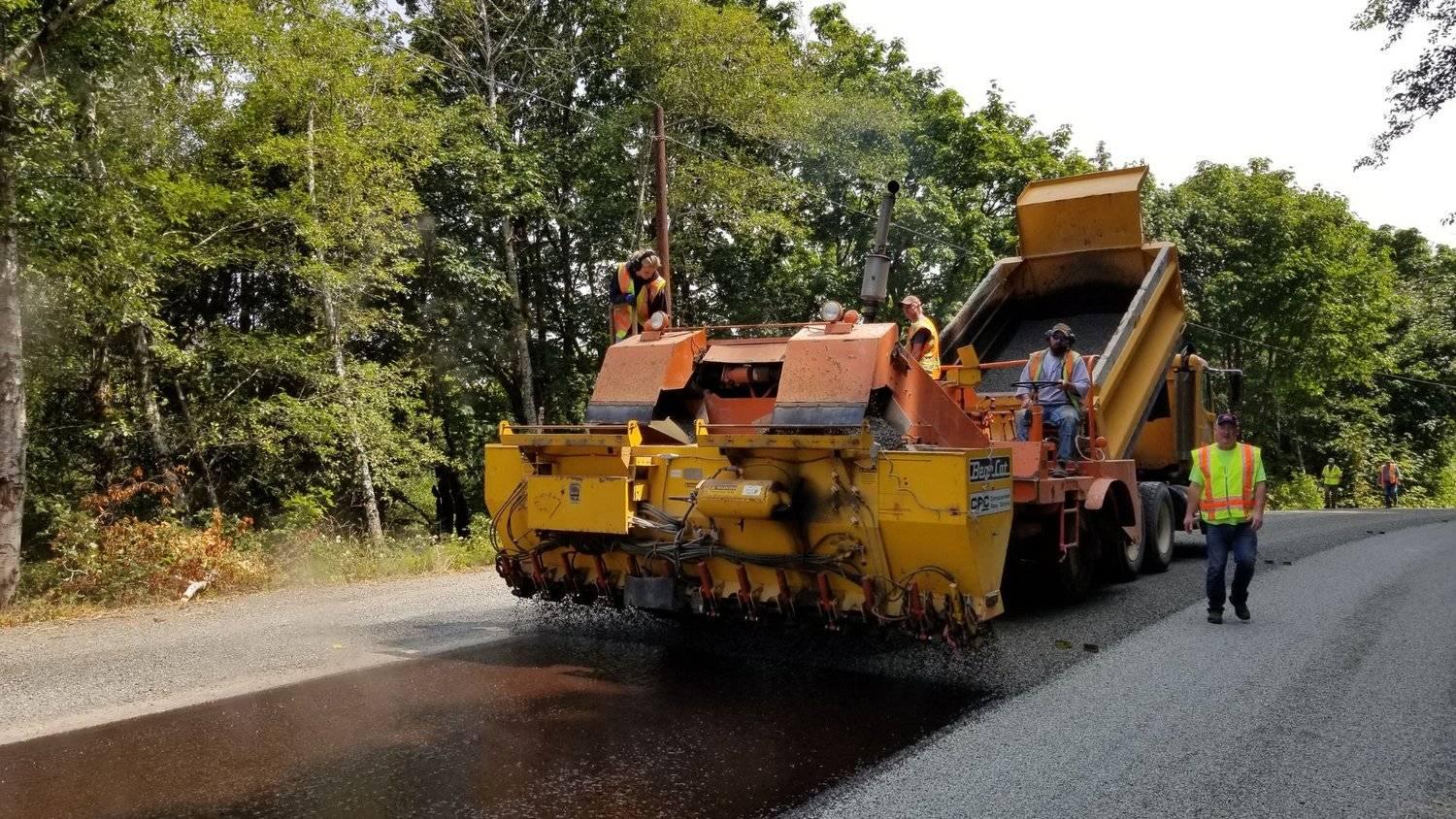 Paving crew operating heavy machinery during asphalt laneway resurfacing and road maintenance.
